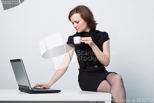 Image of sitting on the table an girl with a laptop and a cup of coffee