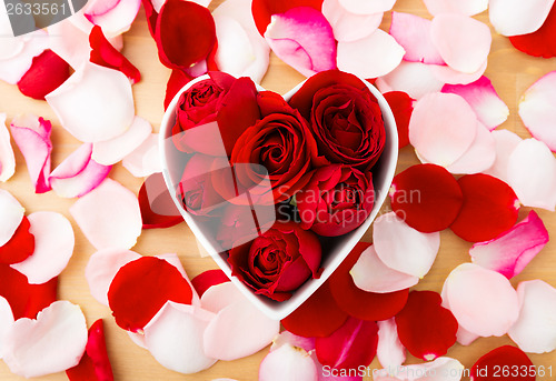 Image of Red rose inside the heart shape bowl with petal beside