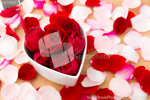 Image of Beautiful Red rose inside heart shape bowl with petal beside