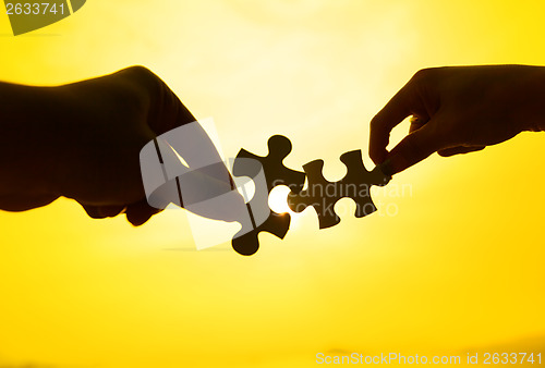 Image of Silhouette of two hands connect puzzle together