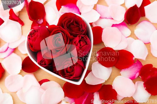 Image of Beautiful Red rose inside the heart shape bowl with petal beside