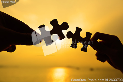 Image of Silhouette of two hands connect jigsaw together