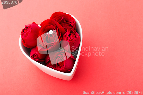 Image of Red rose and diamond ring inside heart shape bowl over the red b