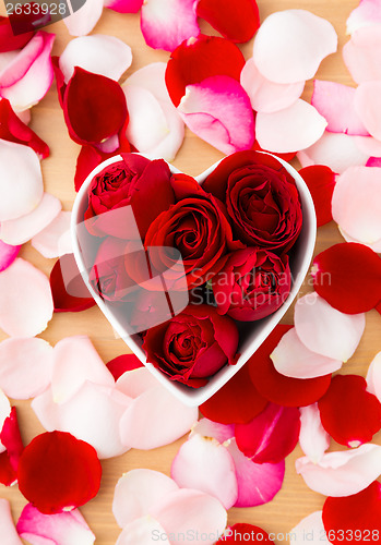 Image of Red rose inside the heart shape bowl with pink petal beside