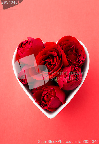 Image of Red rose inside the heart shape bowl with red background
