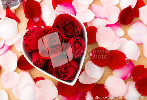 Image of Beautiful Red rose inside the heart shape bowl with petal beside