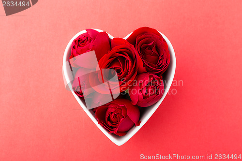 Image of Red rose inside heart shape bowl on red background