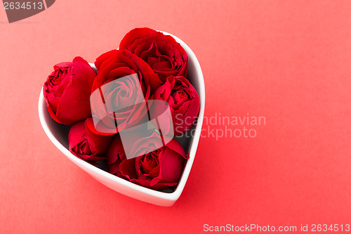 Image of Rose inside the heart shape bowl over the red background