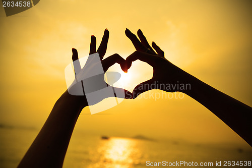 Image of Silhouette hand in heart shape during sunset
