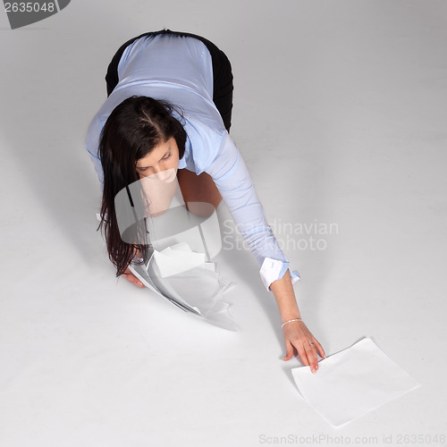 Image of Young woman raised fallen documents