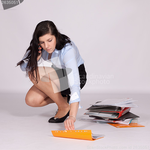 Image of Young woman in mini skirt and blouse, squatting rises from the g