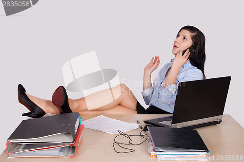 Image of Young female office worker with feet on desk