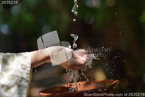 Image of splashing fresh water on woman hands