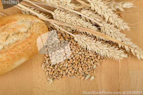 Image of roll on wooden table with ears of wheat grain