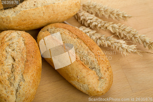 Image of roll on wooden table with ears of wheat grain