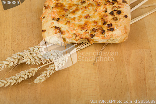 Image of Freshly bread with cheese and onion on wooden table with ears