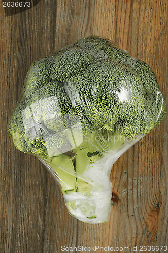 Image of cabbage broccoli in plastic bag on a wooden background