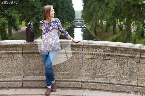 Image of Beautiful young girl on the old stone bridge