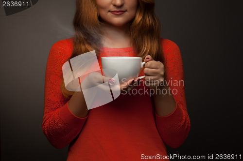 Image of woman holding hot cup and smiles