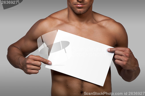Image of Muscular naked man holding white empty paper