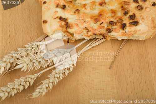 Image of Freshly bread with cheese and onion on wooden table with ears