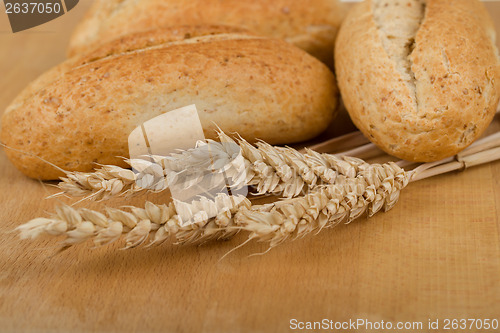 Image of roll on wooden table with ears of wheat grain