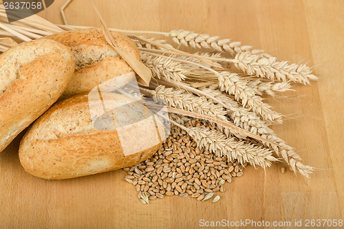 Image of roll on wooden table with ears of wheat grain