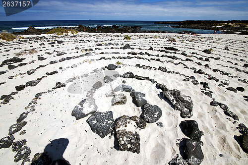 Image of spiral of black rocks in the white  beach   lanzarote 