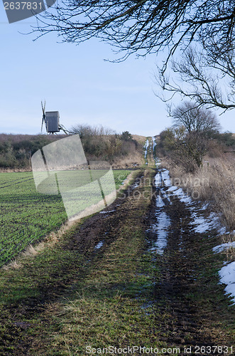 Image of Windmill at a dirt road in springtime