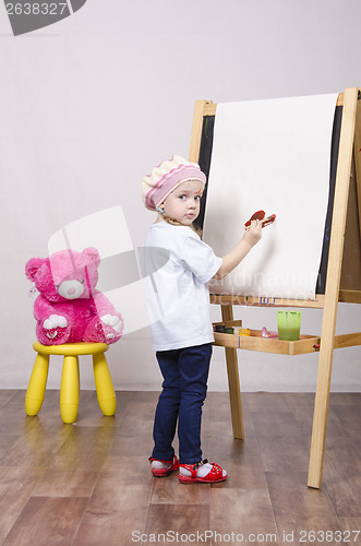 Image of Girl, the artist draws on easel bear