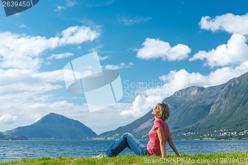 Image of Woman relaxing enjoying at the fjord coast