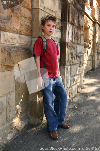 Image of Youth leaning against sandstone wall