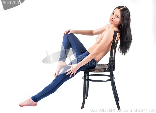 Image of topless woman in jeans sitting on chair