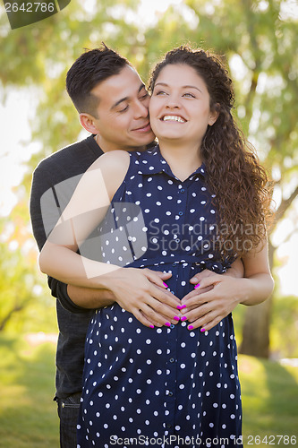 Image of Hispanic Man Hugs His Pregnant Wife Outdoors At the Park