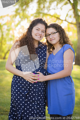 Image of Hispanic Daughter Feels Baby Kick in Pregnant Mother’s Tummy 