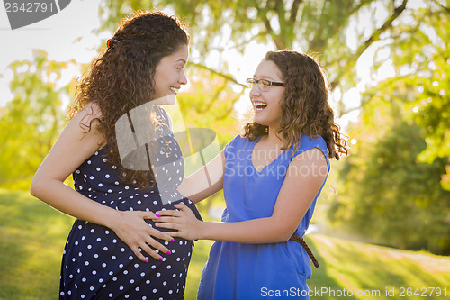 Image of Hispanic Daughter Feels Baby Kick in Pregnant Mother’s Tummy 