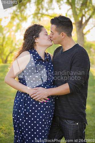 Image of Hispanic Man Kisses His Pregnant Wife Outdoors At the Park