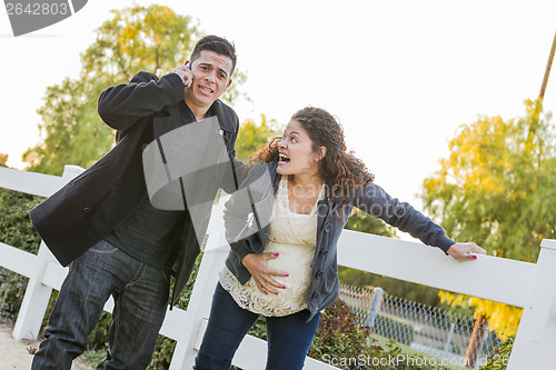 Image of Pregnant Woman In Pain While Husband Uses Cell Phone Outside