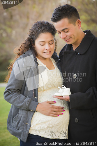 Image of Hispanic Pregnant Couple Holding Baby Shoes Outside