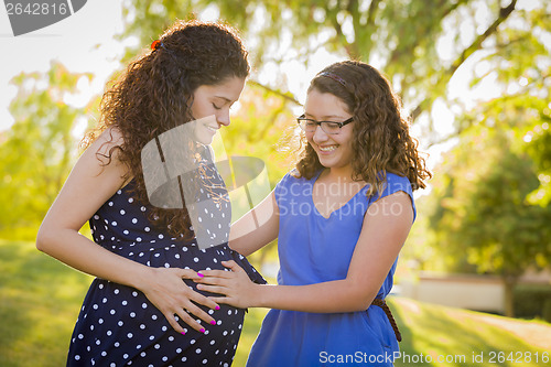 Image of Hispanic Daughter Feels Baby Kick in Pregnant Mother’s Tummy 