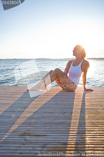 Image of Attractive woman sitting on pier