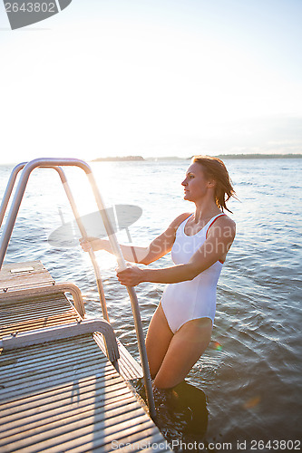 Image of Attractive woman climbing ladder to pier