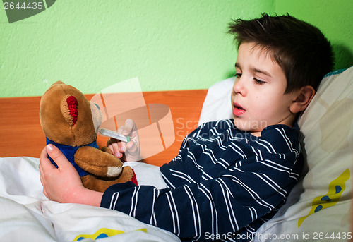 Image of Sick child in bed with teddy bear