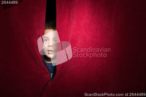 Image of Child appearing beneath the curtain