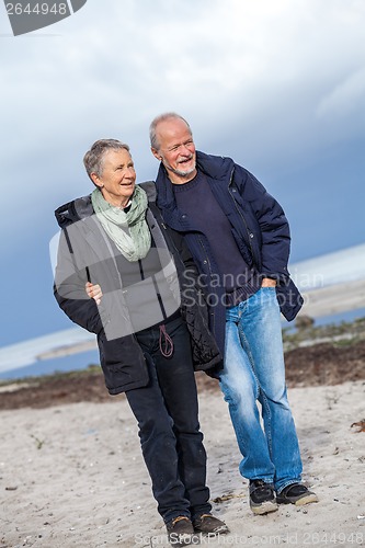 Image of happy elderly senior couple walking on beach