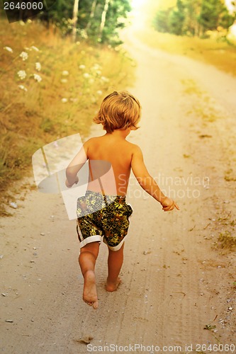 Image of Boy running along road in park, outdoor