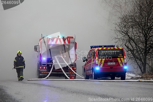 Image of Fireman Emerging from Smoke with Fire Trucks on the Street