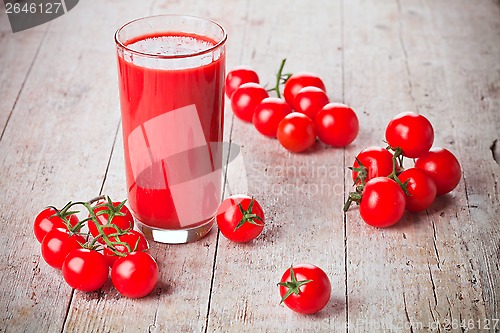 Image of tomato juice in glass and fresh tomatoes