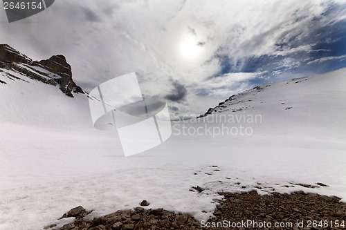 Image of Snowy mountain pass and sky with clouds at evening