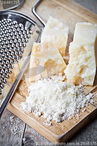 Image of grated parmesan cheese and metal grater 